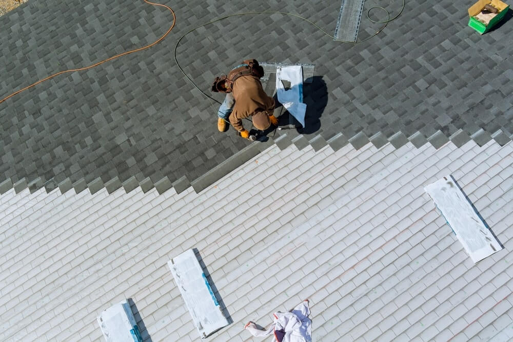 Worker Applying Shingles On Roof