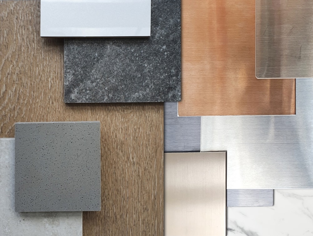 close up view of interior material samples including wood veneer, ceramic tiles, multi color of aluminium metallics, travertine granite tile, artificial stone, white marble. deluxe materials.