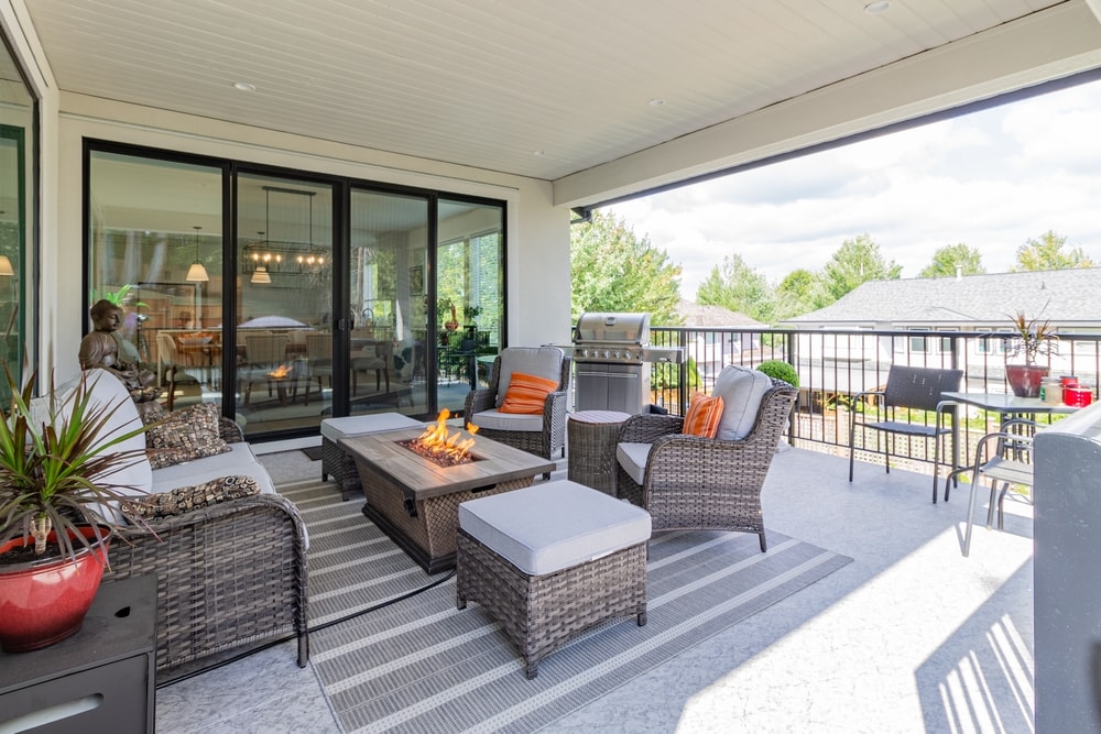 A luxurious spacious deck with stylish patio furniture with a fire pit table heater and  barbecue grill.