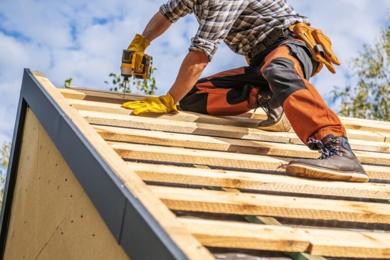 Caucasian Professional Roofing Contractor in His 40s Attaching Wooden Elements to the House Roof