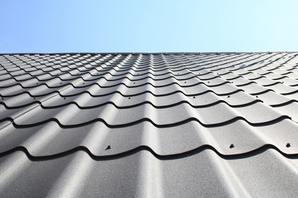 Sunlit metal roof. Bottom view. Grainy texture of metal roof tiles. Shallow depth of field