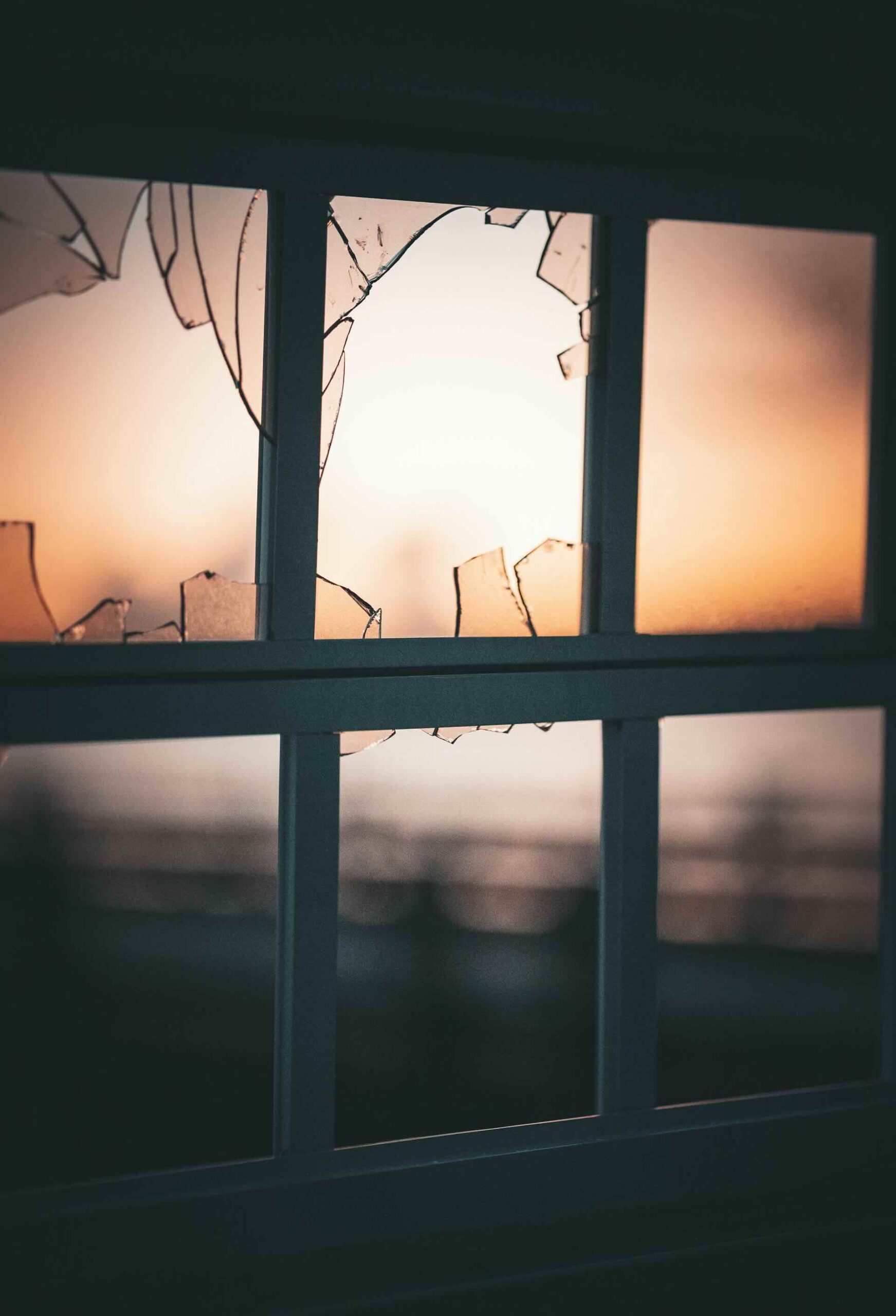 Windows with black frames and broken glass, moody sunset in background - Pinnacle Home Improvements