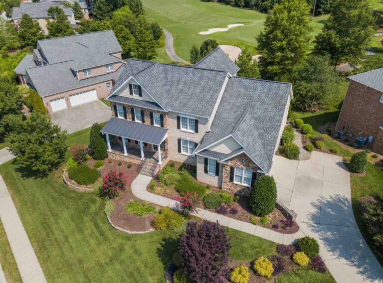 Aerial view of roof of suburban home in Raleigh, NC, amidst green landscaping - Pinnacle Home Improvements