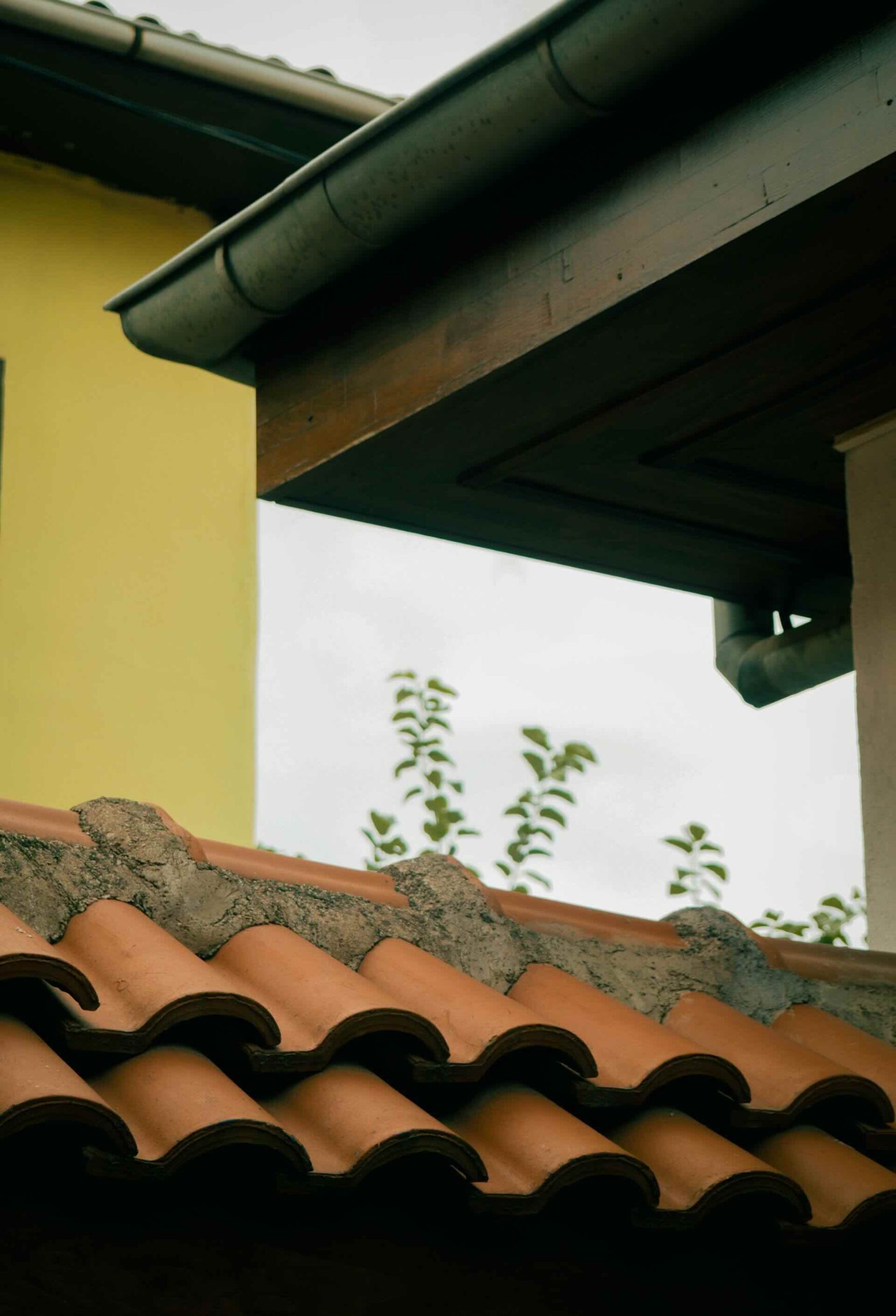 Side view of rooftop with terracotta tiles under cloudy sky - Pinnacle Home Improvements